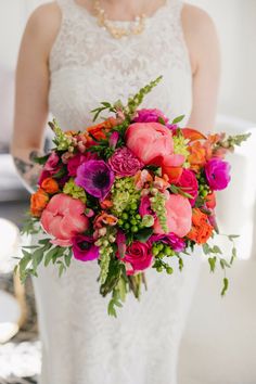 a woman holding a bouquet of pink and orange flowers on her wedding day at the hotel