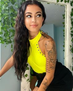 a woman with tattoos on her arm posing for a photo in front of a mirror