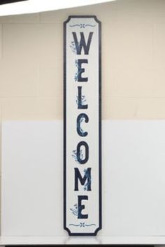 a welcome sign hanging from the side of a wall in front of a door way