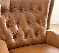 a brown leather chair sitting on top of a hard wood floor