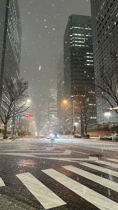 a city street filled with lots of traffic and tall buildings covered in snow at night