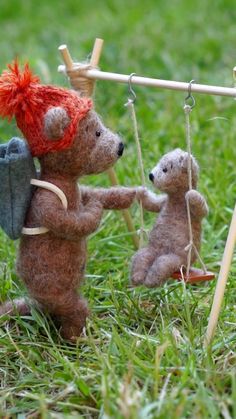 two teddy bears hanging on to clothes pins in the grass with one holding an umbrella