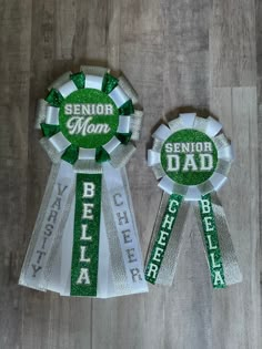 two ribbons with the words senior dad and cheerleader on them, sitting on a wooden floor