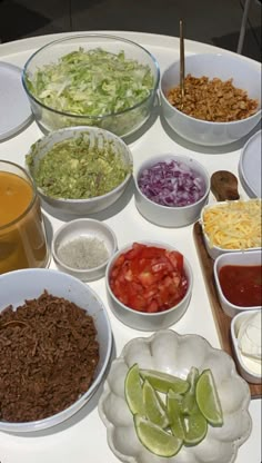 a white table topped with bowls filled with different types of food and condiments