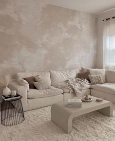 a living room filled with white furniture next to a wall covered in papered walls