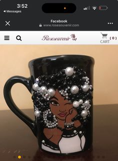 a black coffee mug decorated with pearls and beaded hair on top of a table