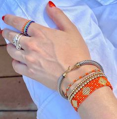 Outstanding Orange Beaded Jewels Band: Flat woven; 1/2"w; 14K yellow/rose gold-filled or sterling silver clasp & 1" extender chain; glass seed beads. Strands: Stretch style; 14K yellow/rose gold-filled or sterling silver round 2mm, 3mm & 4mm beads; glass seed beads. Wrap: Stretch style that will wrap around the wrist 3 times (can also be worn as a necklace); glass seed beads. (When adding to cart, select your single bracelet size, and it will be multiplied in length by three when made). Shown in Orange Beaded Bracelets For Everyday Wear, Gold Braided Bracelets With Tiny Beads, Yellow Gold Jewelry With Colorful Beads, Yellow Gold Beaded Bracelet With Tiny Beads, Everyday Braided Bracelets With Tiny Beads, Everyday Tiny Beads Braided Bracelet, Orange Stackable Jewelry With Round Beads, Orange Stackable Round Bead Jewelry, Woven Beaded Bracelets