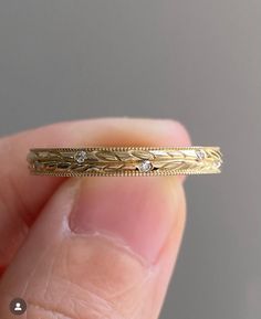 a close up of a person's hand holding a gold ring with diamonds on it