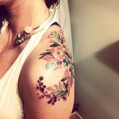 a woman with a flower tattoo on her arm and shoulder is looking at the camera