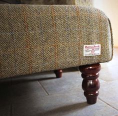 a close up of a footstool on the floor with a brown and tan tweed cover