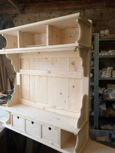 an unfinished wooden shelf with drawers and shelves