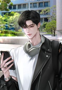 a young man wearing headphones looking at his cell phone while standing in front of a building