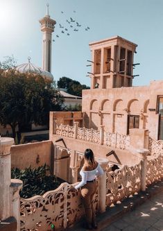 a woman sitting on a balcony next to a building