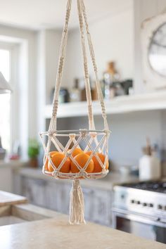 some oranges are in a hanging basket on the counter