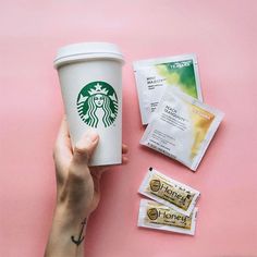 a hand holding a starbucks cup next to some snacks