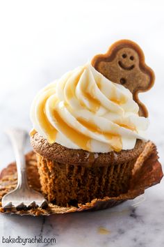 there is a cupcake with icing and a ginger face on top, next to a spoon