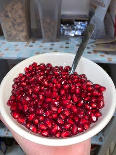 a person holding a bowl full of pomegranates with a knife in it