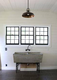 a bathroom with two windows and a sink in the middle, under a light fixture