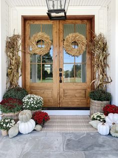 the front door is decorated with wreaths and pumpkins