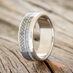 a wedding ring with an intricate design on the outside and inside, sitting on a piece of wood