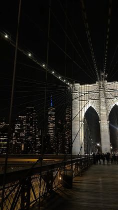 people walking across the brooklyn bridge at night