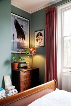 a bed room with a neatly made bed next to a window and a poster on the wall