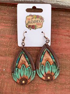 the earrings are made from wood and painted with turquoise, green and brown flowers on them