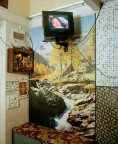 a television mounted to the side of a wall next to a bench with a painting on it