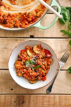 two bowls filled with food sitting on top of a wooden table next to utensils