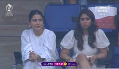 two women sitting next to each other at a tennis match