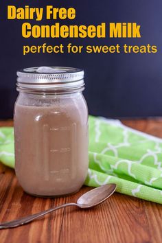 a glass jar filled with milk sitting on top of a table next to a spoon