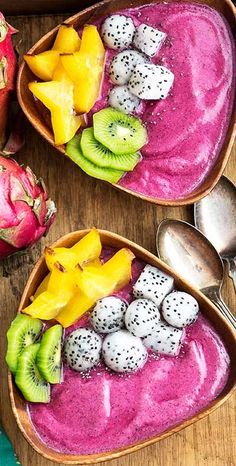 two bowls filled with fruit and topped with kiwis, bananas, and other fruits