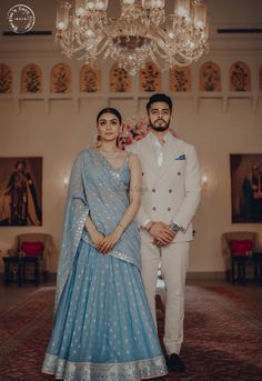 a man and woman standing next to each other in front of a chandelier