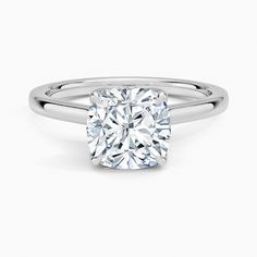 a cushion cut diamond ring on a white background with the center stone in the middle