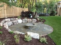 a stone fire pit in the middle of a yard