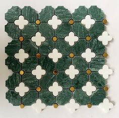 a green and white tile design with gold dots on the edges is shown in this image