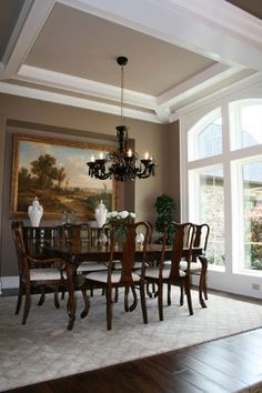 a dining room table with chairs and chandelier in front of large windows that look out onto the outdoors