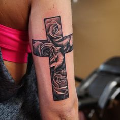 a woman with a cross tattoo on her arm and roses in the middle of it