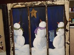 two snowmen are standing in front of a window decorated with blue and white paint