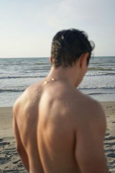 a man standing on top of a sandy beach next to the ocean