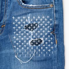 the back pocket of a pair of jeans with cross stitchs and holes in it