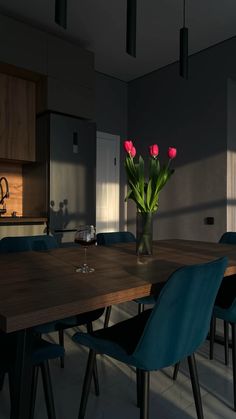 a dining room table with blue chairs and a vase full of flowers on the table