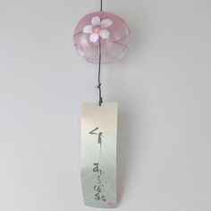 a pink flower hanging from the side of a wall next to a tag with chinese writing on it