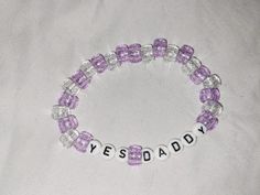 a purple and white beaded bracelet with the word yes daddy spelled in small beads