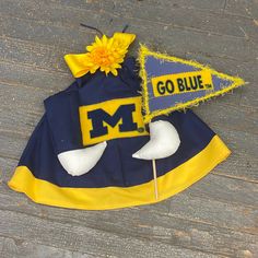 a blue and yellow hat with a flower on it sitting on top of a wooden floor