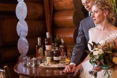 a bride and groom standing in front of a table with liquor bottles on the table