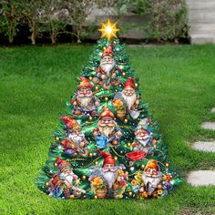 a small christmas tree with gnomes and stars on it in the middle of grass