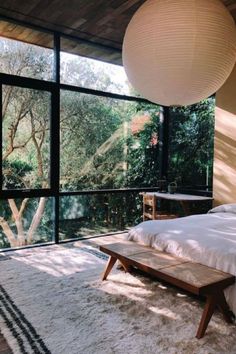 a bed sitting in a bedroom next to a window covered in white blankets and pillows