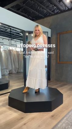 a woman standing in front of a dress on display