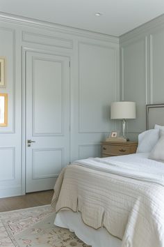 a white bed sitting in a bedroom on top of a wooden floor next to two doors